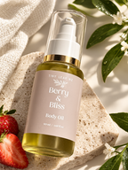 A bottle of Tiny Leaf Wz Berry & Bliss Body Oil, 50ml, featuring a pale pink label and gold collar, styled on a textured stone slab with strawberries, green leaves, and a cream-colored towel.