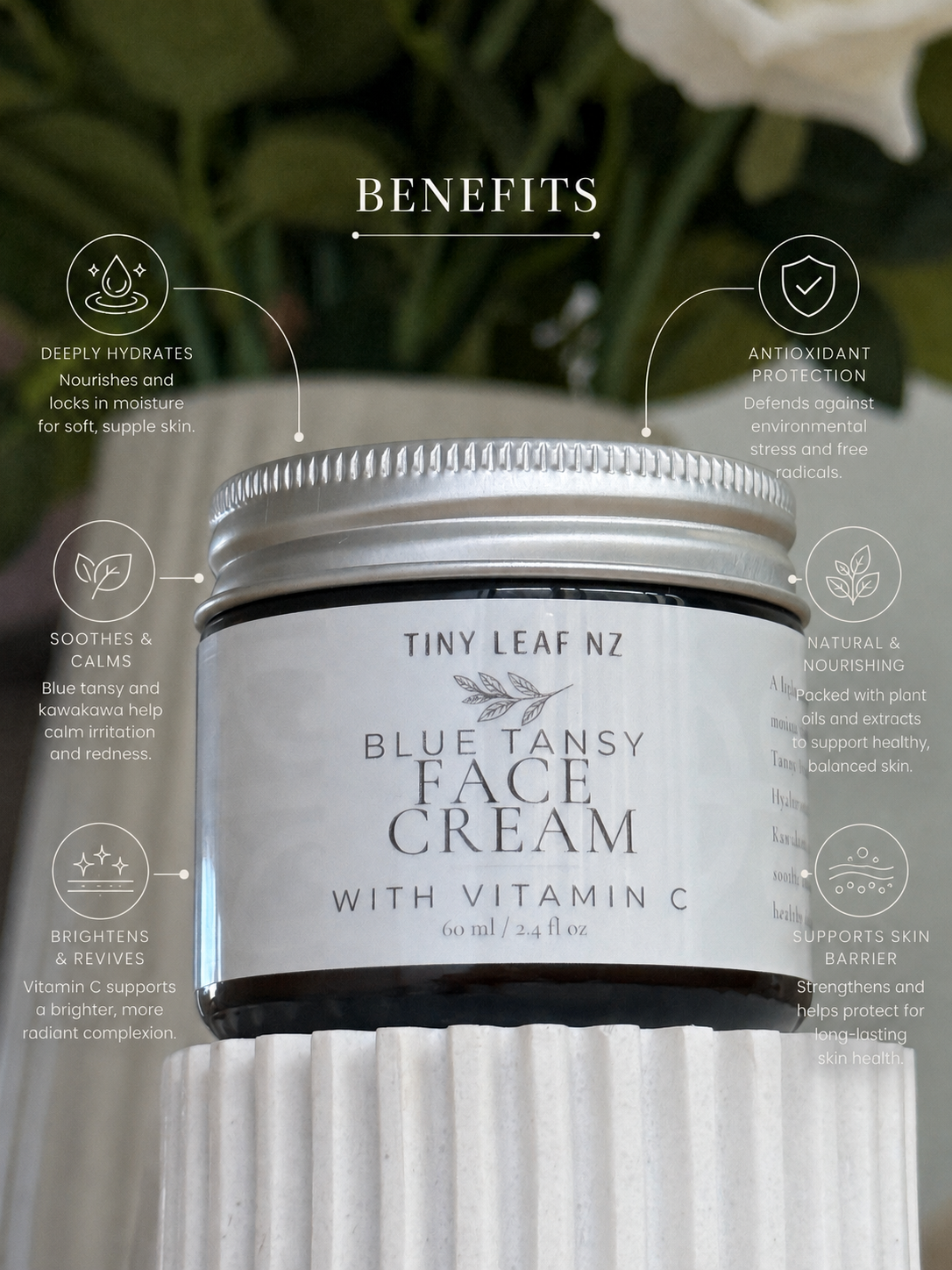 A jar of Tiny Leaf Nz Blue Tansy Face Cream with Vitamin C, displayed on a white ribbed pedestal with graphic benefit callouts overlaid on a blurred green and white background.