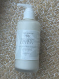 A 200ml pump bottle of Tiny Leaf Nz Kawakawa Oat Daily Lotion, filled with a milky white lotion, resting on a woven straw mat.