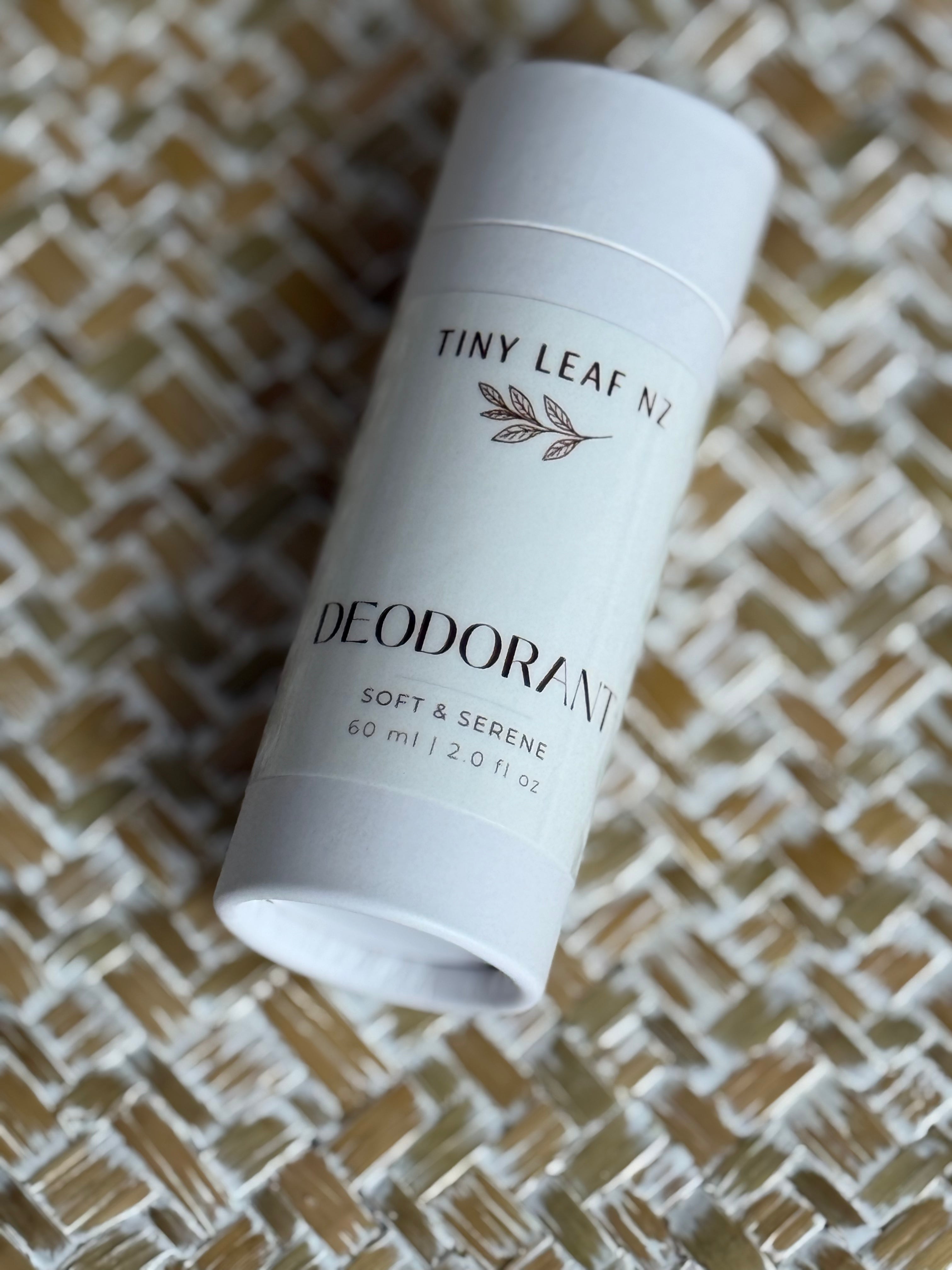 A white cylindrical deodorant stick labeled 'TINY LEAF NZ' and 'DEODORANT' resting on a woven beige and white textured mat.