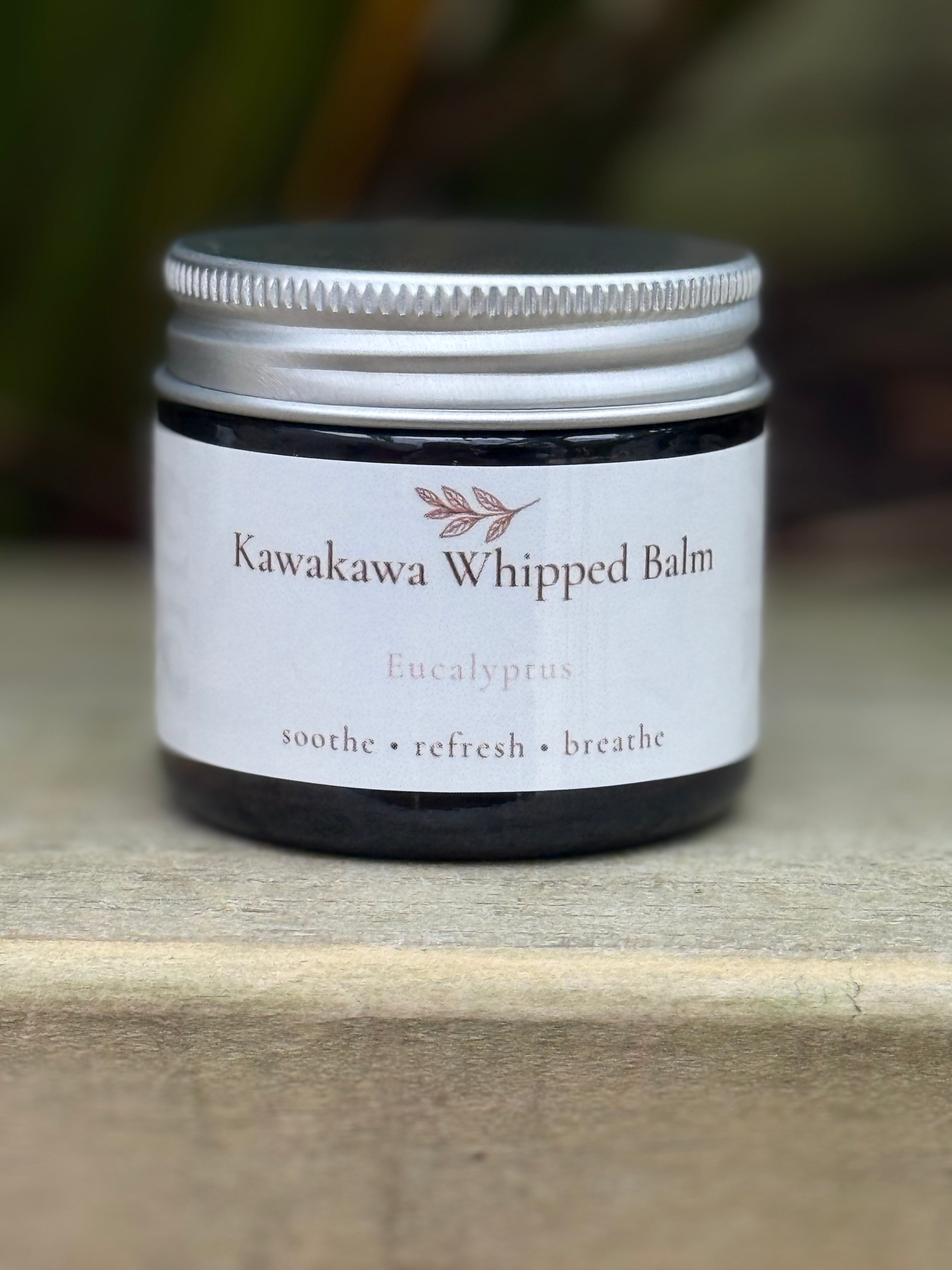 Jar of Kawakawa Whipped Balm with a white label on a wooden surface