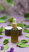 Glass dropper bottle with wooden cap on a wooden surface with two small containers in the background.