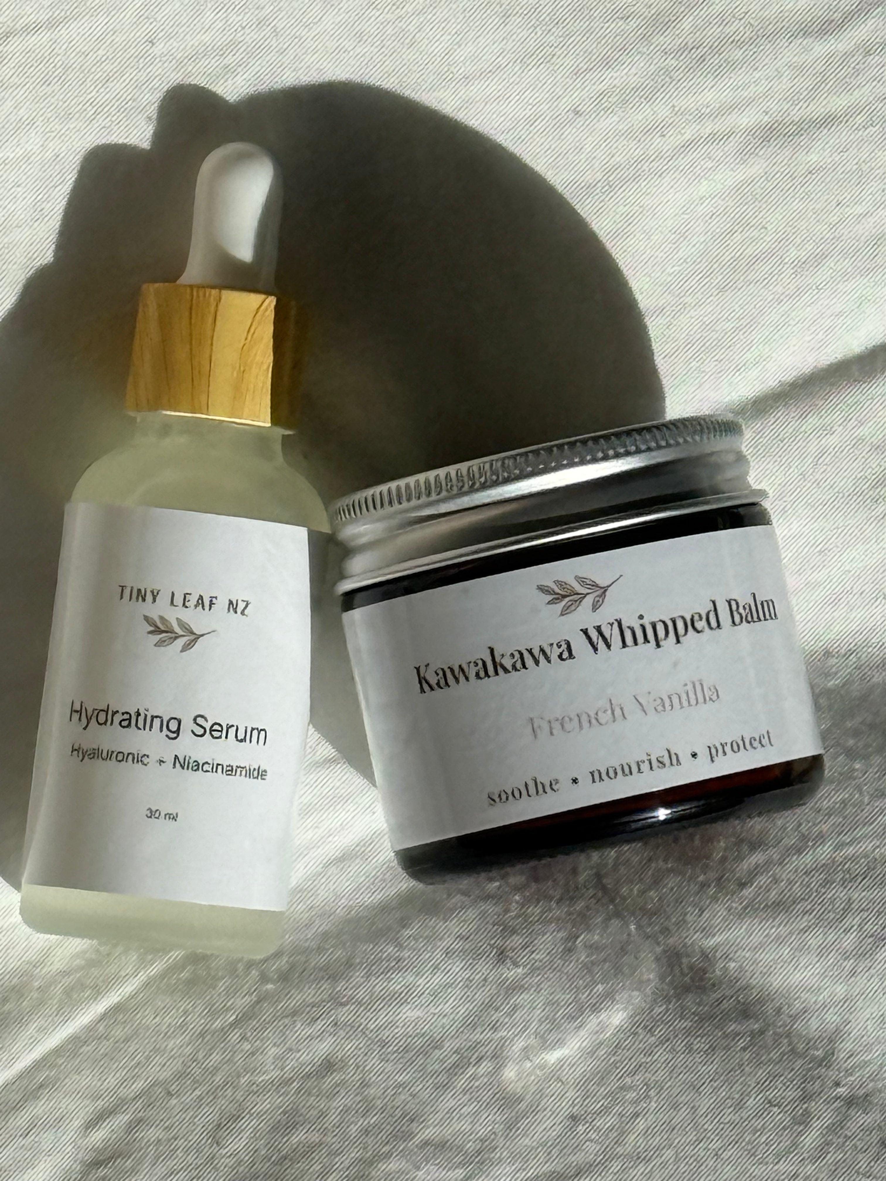 Hydrating Serum and Kawakawa Whipped Balm on a textured surface