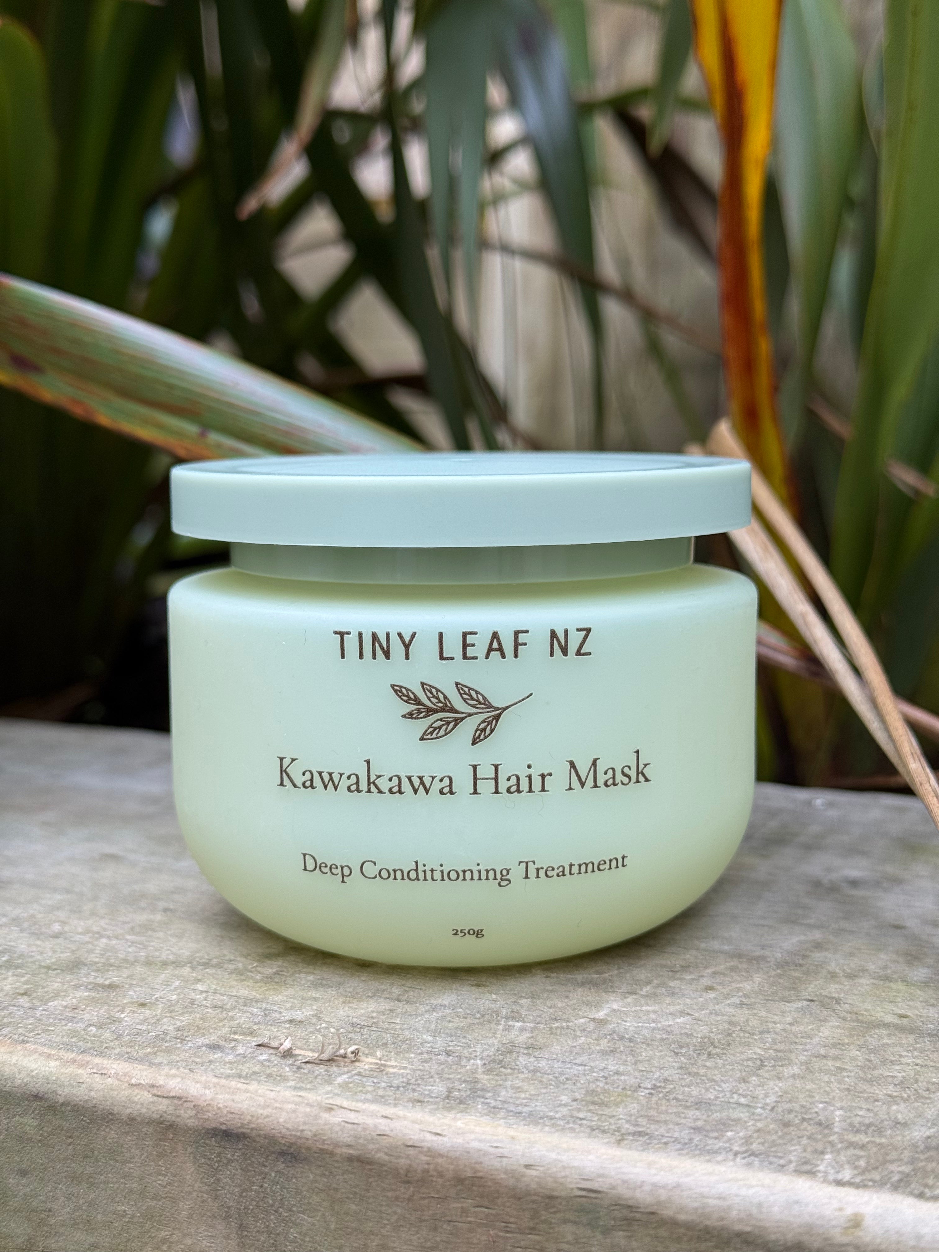 A jar of Tiny Leaf NZ Kawakawa Hair Mask deep conditioning treatment, placed on a stone surface with green foliage in the background.