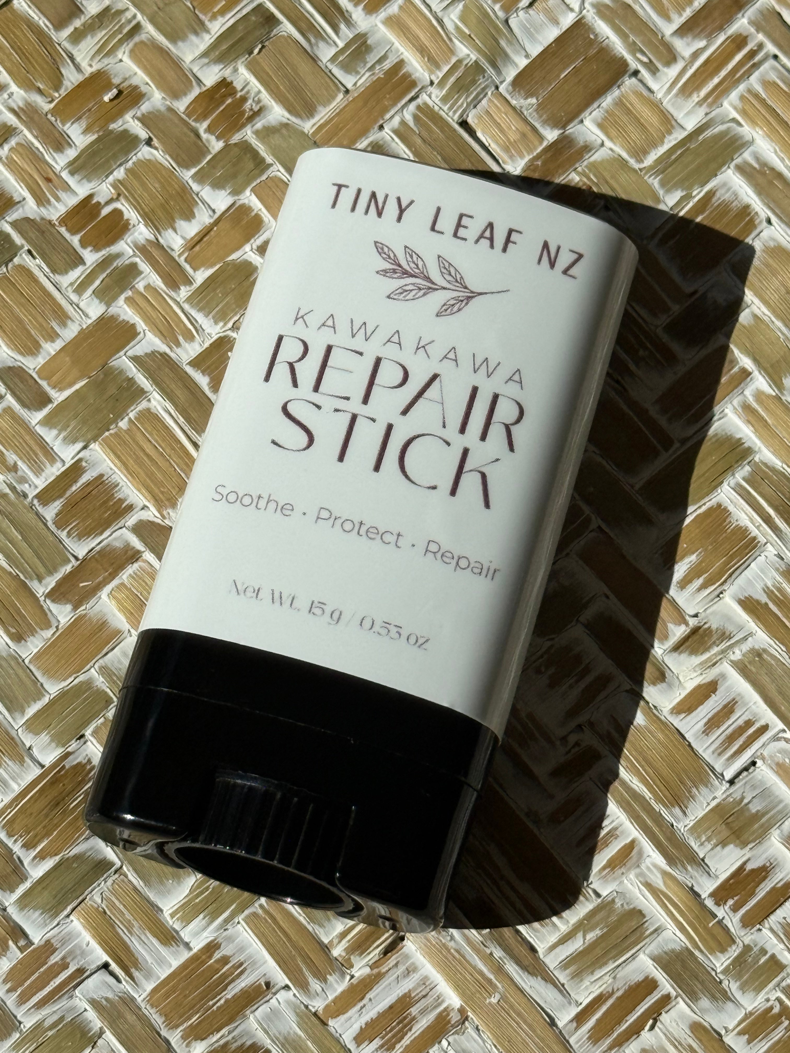A deodorant stick labeled 'Tiny Leaf Nz Kawakawa Repair Stick' resting on a woven straw mat under direct sunlight.