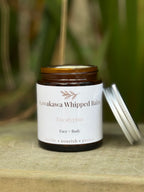Jar of Kawakawa Whipped Balm with a white label on a wooden surface