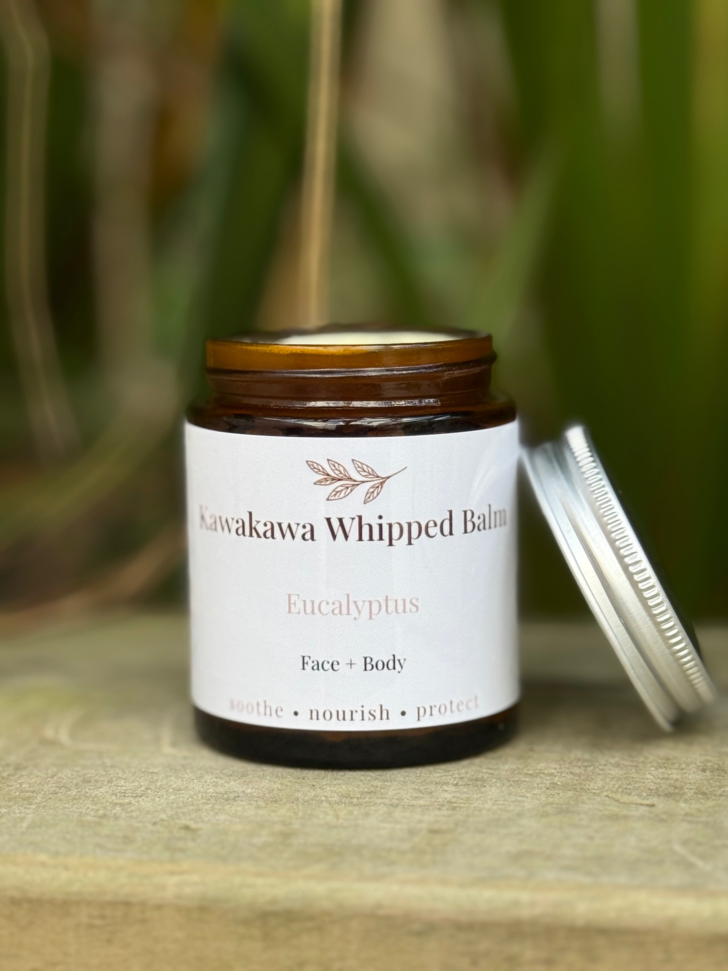 Jar of Kawakawa Whipped Balm with a white label on a wooden surface