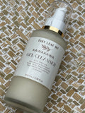 A bottle of Tiny Leaf Nz Kawakawa Gel Cleanser with a white pump and gold collar, resting on a woven straw mat background.