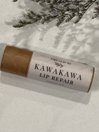 Kawakawa lip repair stick with brown paper wrap on a light surface