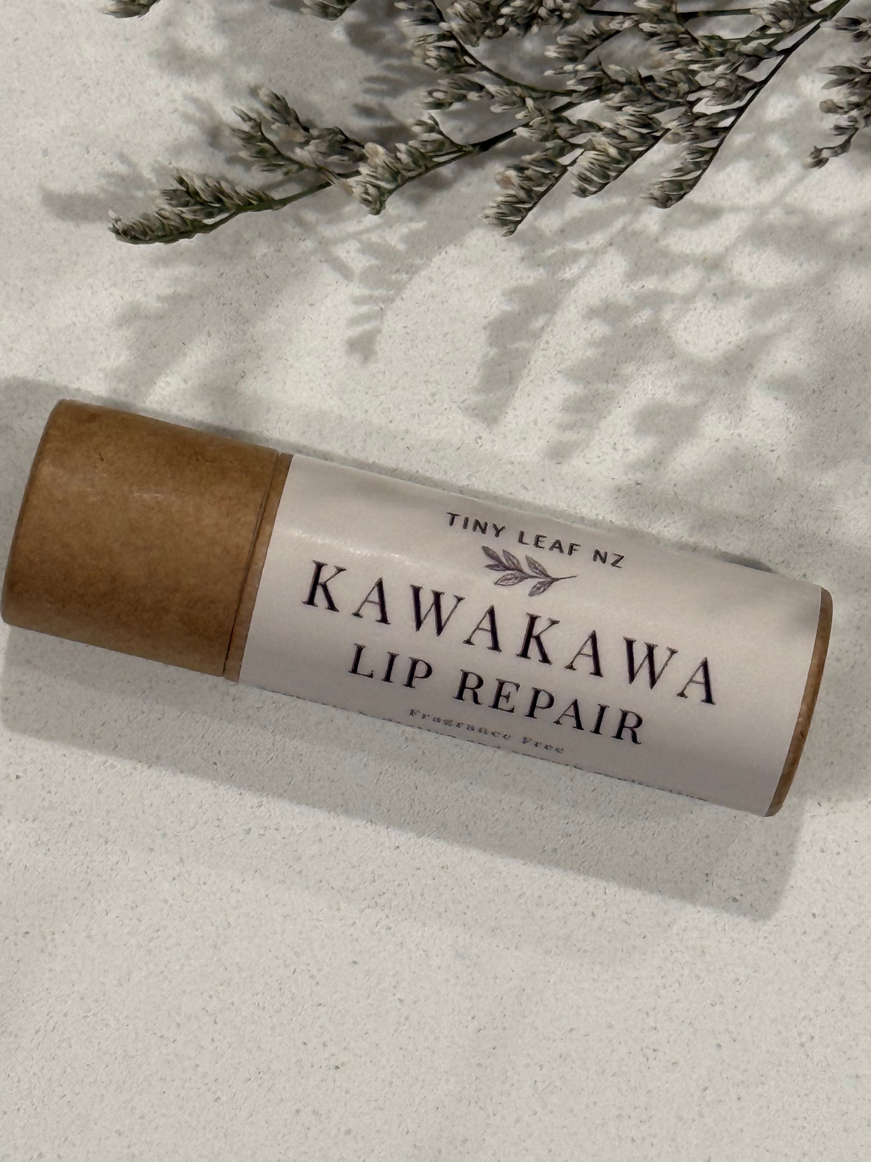 Kawakawa lip repair stick with brown paper wrap on a light surface