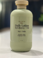 Minimalist product photo of Tiny Leaf NZ Daily Lotion Kawakawa + Oat in a soft sage green bottle on a white marble stone
