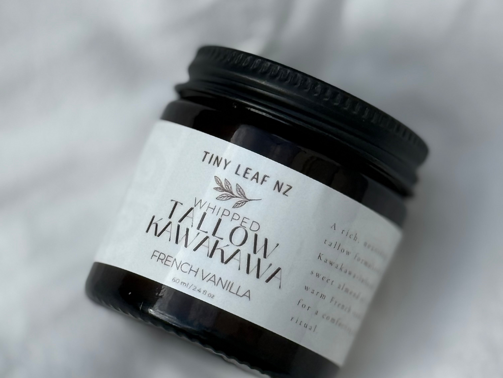 A small black jar of Tiny Leaf NZ Wicked Mañara French Vanilla body butter resting on a textured white fabric background.