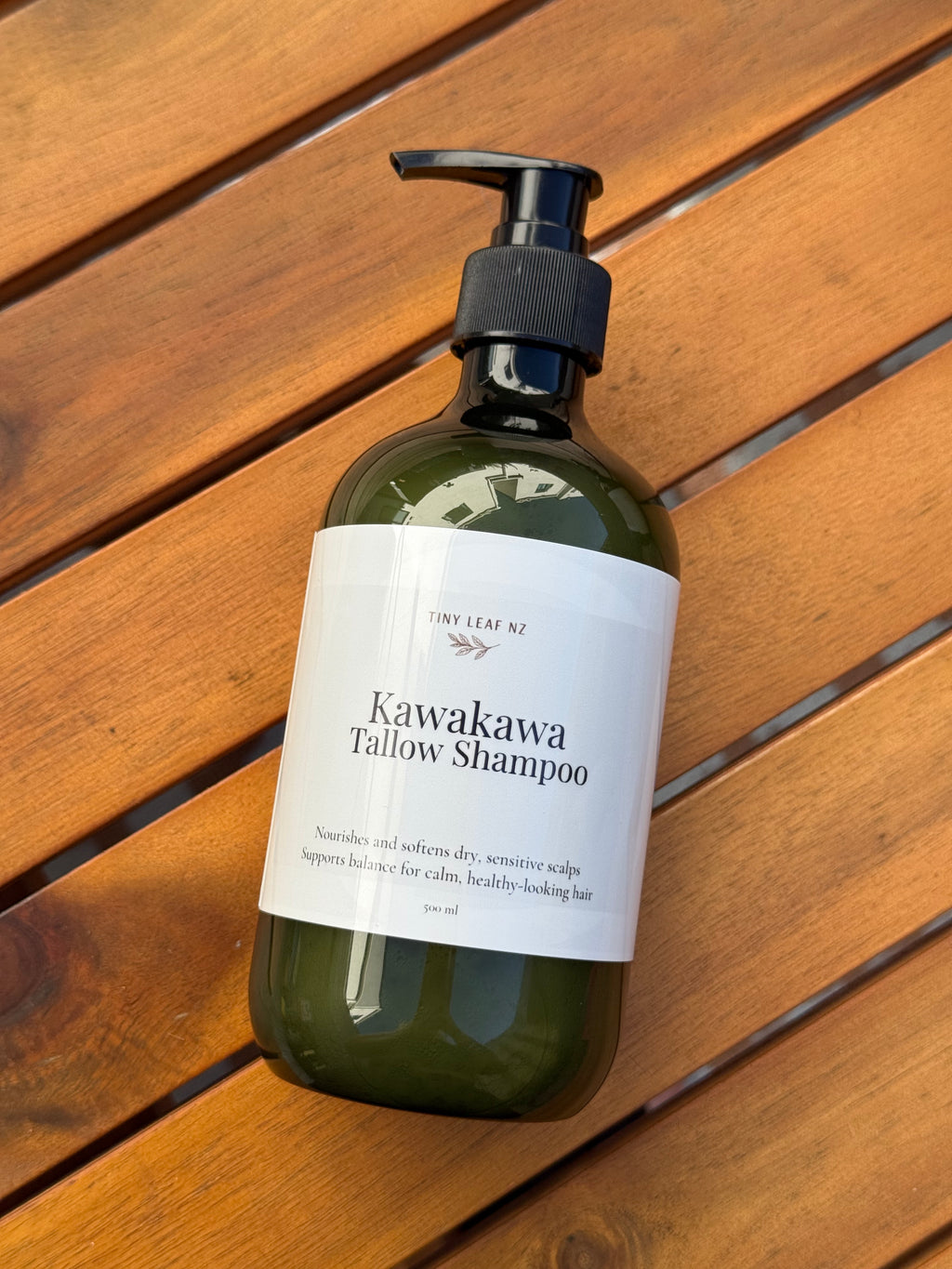 Bottle of Kawakawa Tallow Shampoo on a wooden surface