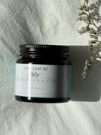 Jar of Tiny leaf NZ Kawakawa + Zinc balm on a textured surface with a branch in the corner.
