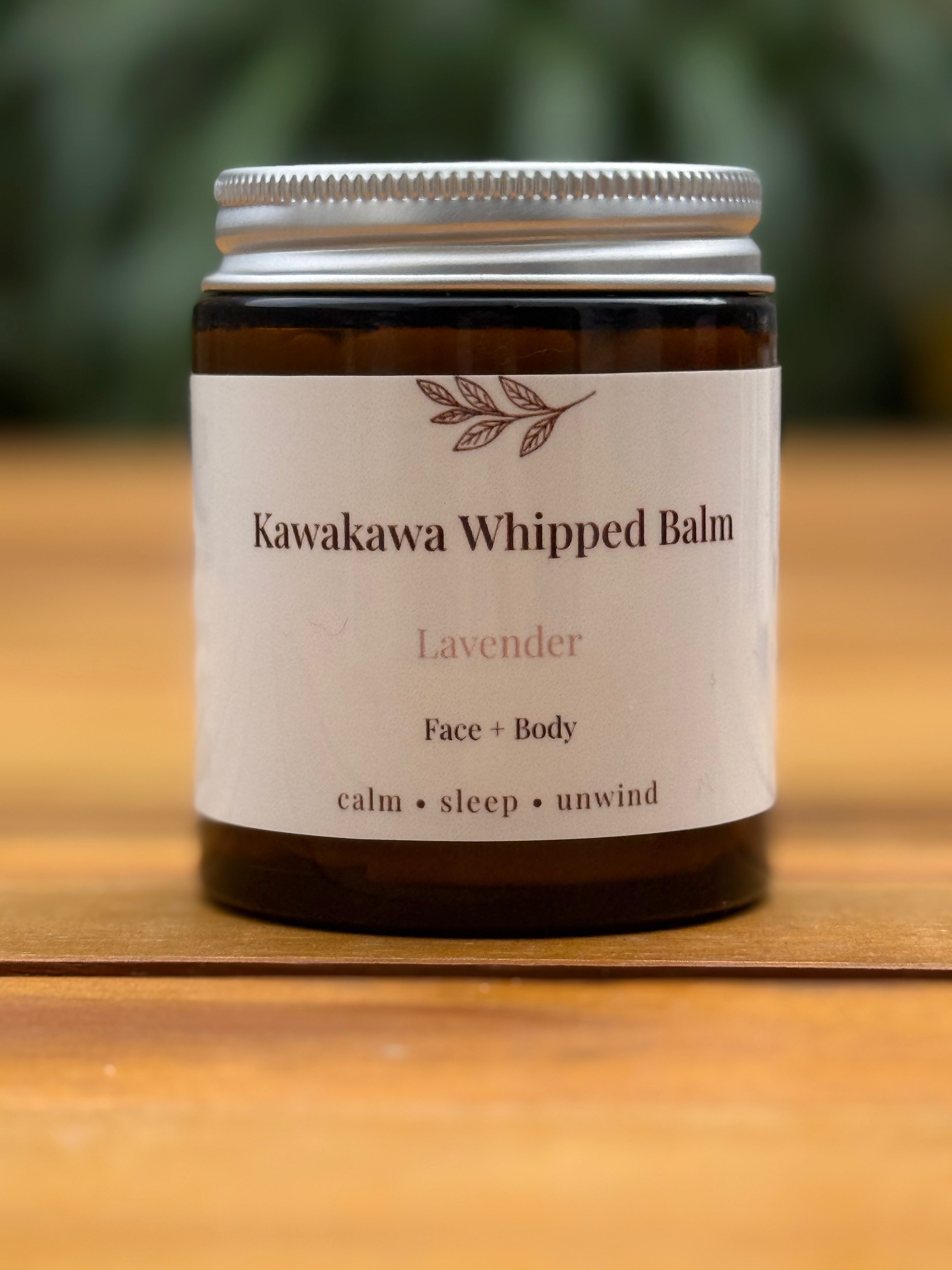 Jar of Kawakawa Whipped Balm with a white label on a wooden surface