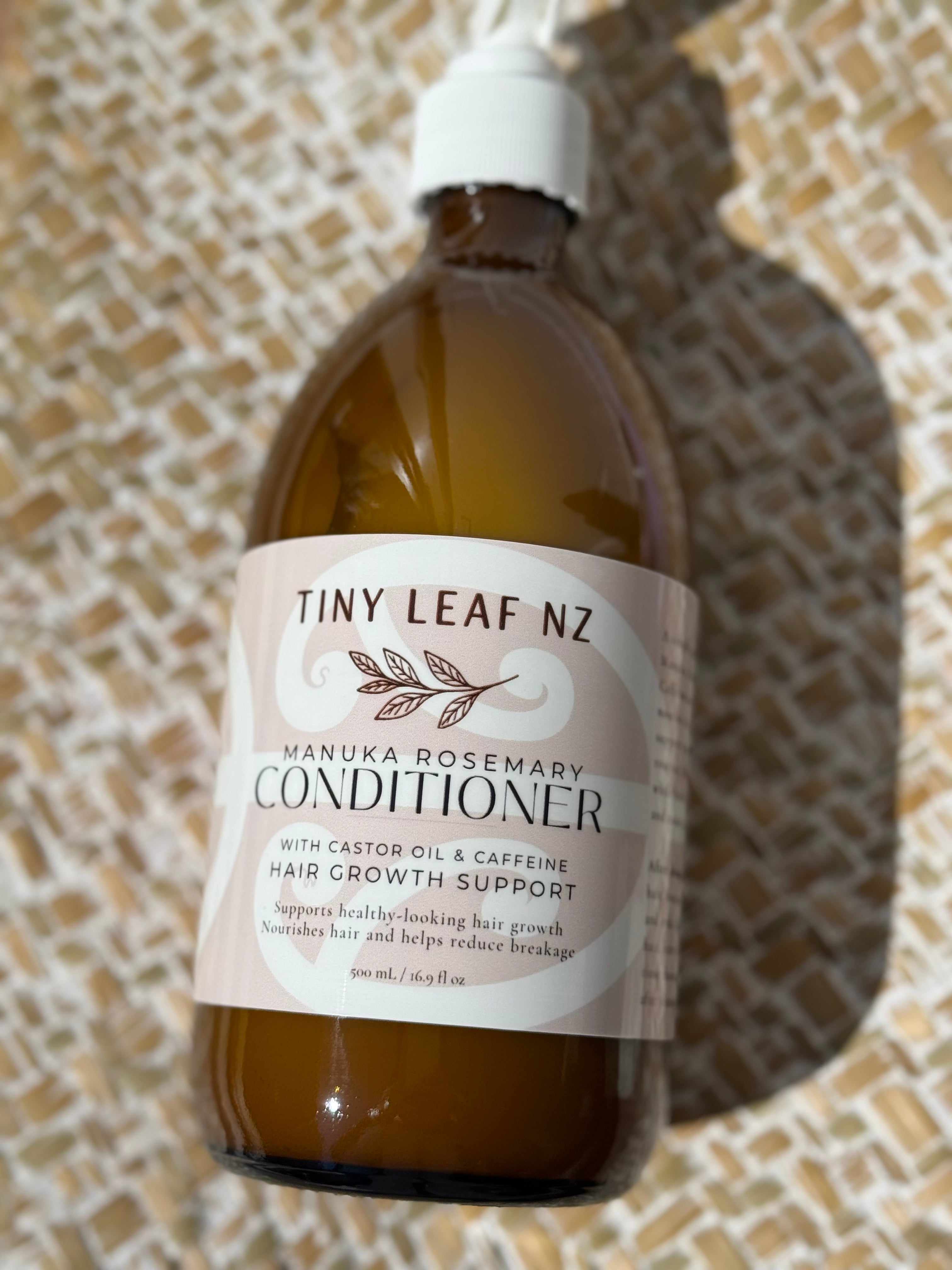A bottle of Tiny Leaf NZ Manuka Rosemary Conditioner with Castor Oil and Caffeine, shown on a textured woven mat background.