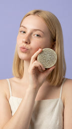 Woman holding a decorative soap bar against a purple background