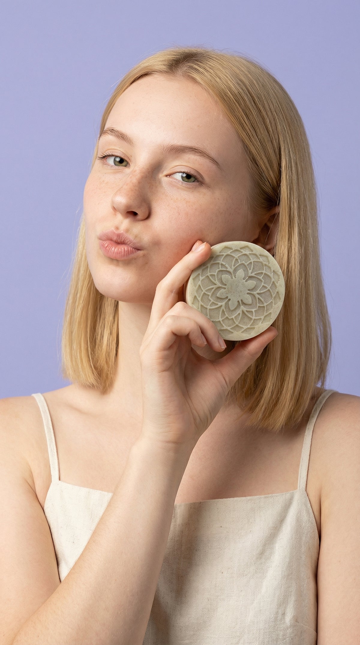 Woman holding a decorative soap bar against a purple background