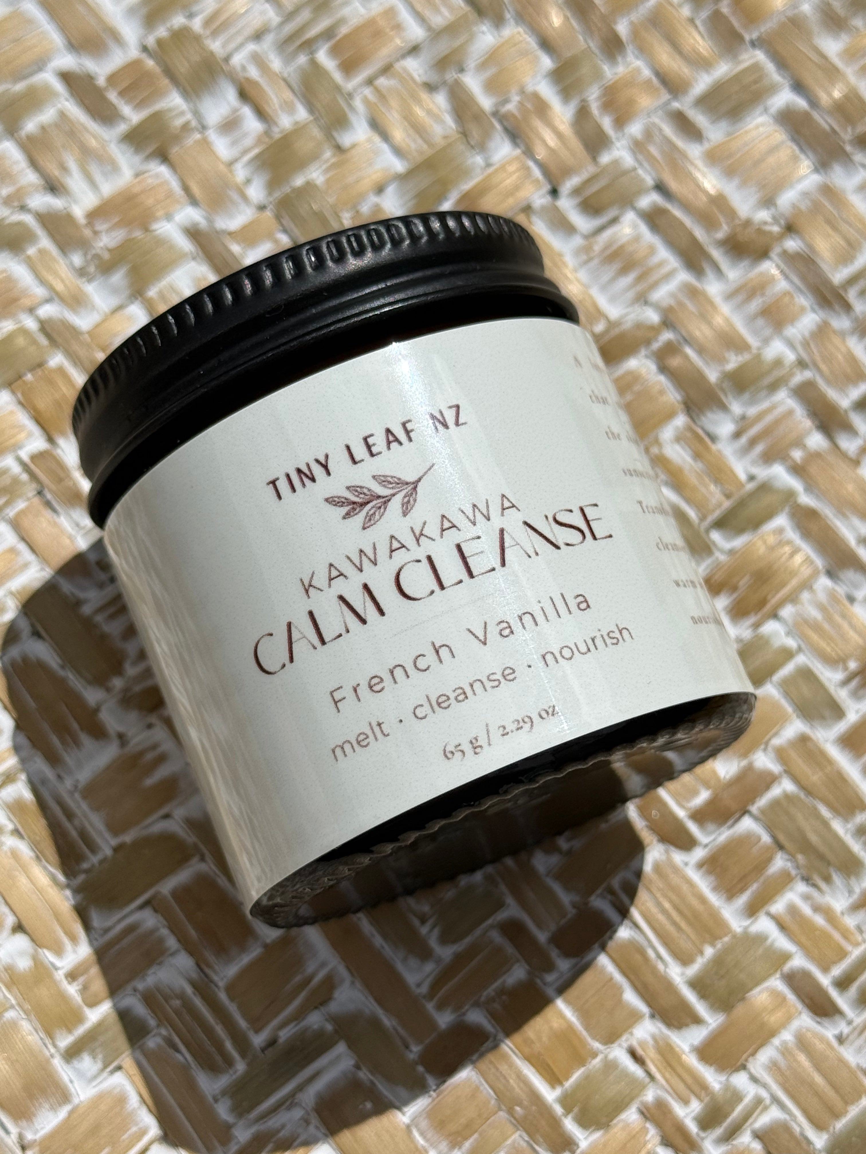 A jar of Tiny Leaf Nz Kawakawa Calm Cleanse French Vanilla melt and cleanse, resting on a woven straw mat.