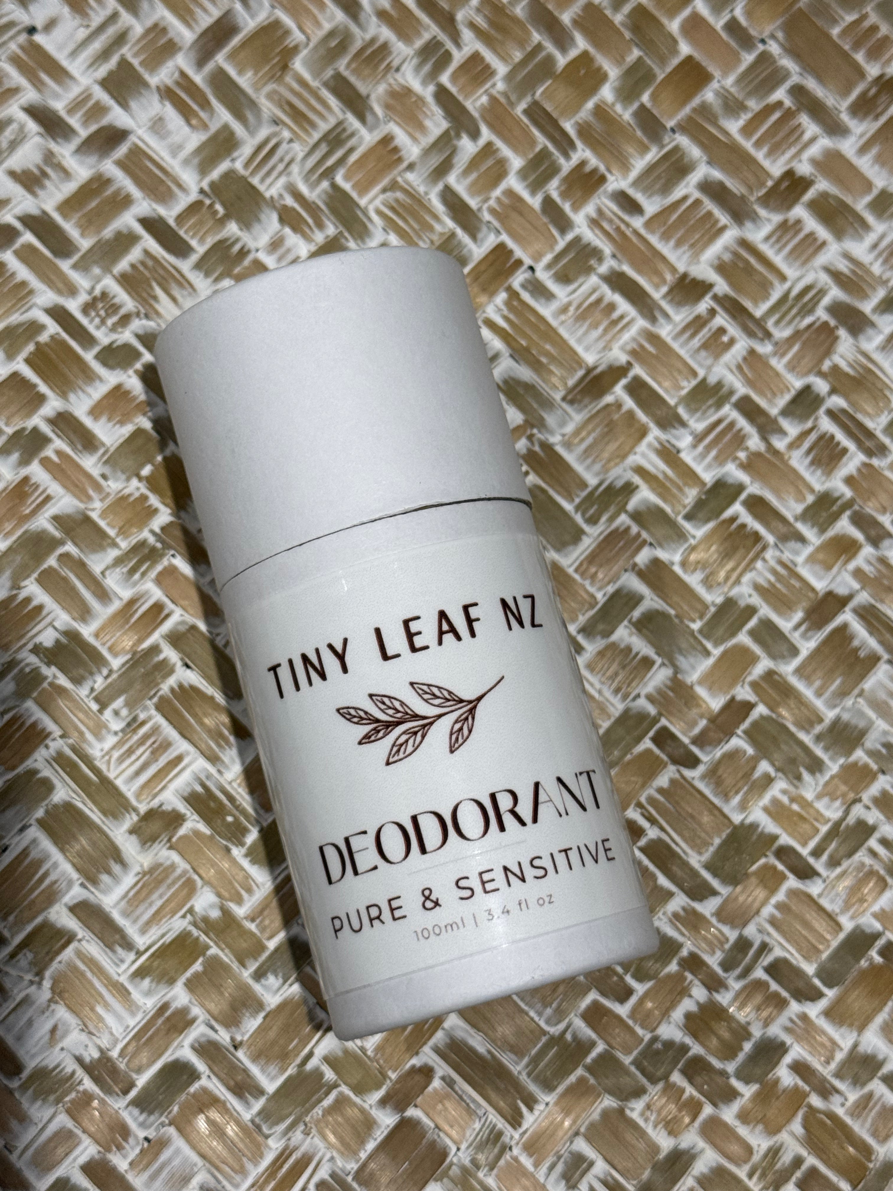 A white roll-on deodorant bottle labeled 'TINY LEAF NZ DEODORANT PURE & SENSITIVE' placed diagonally on a woven straw mat background.