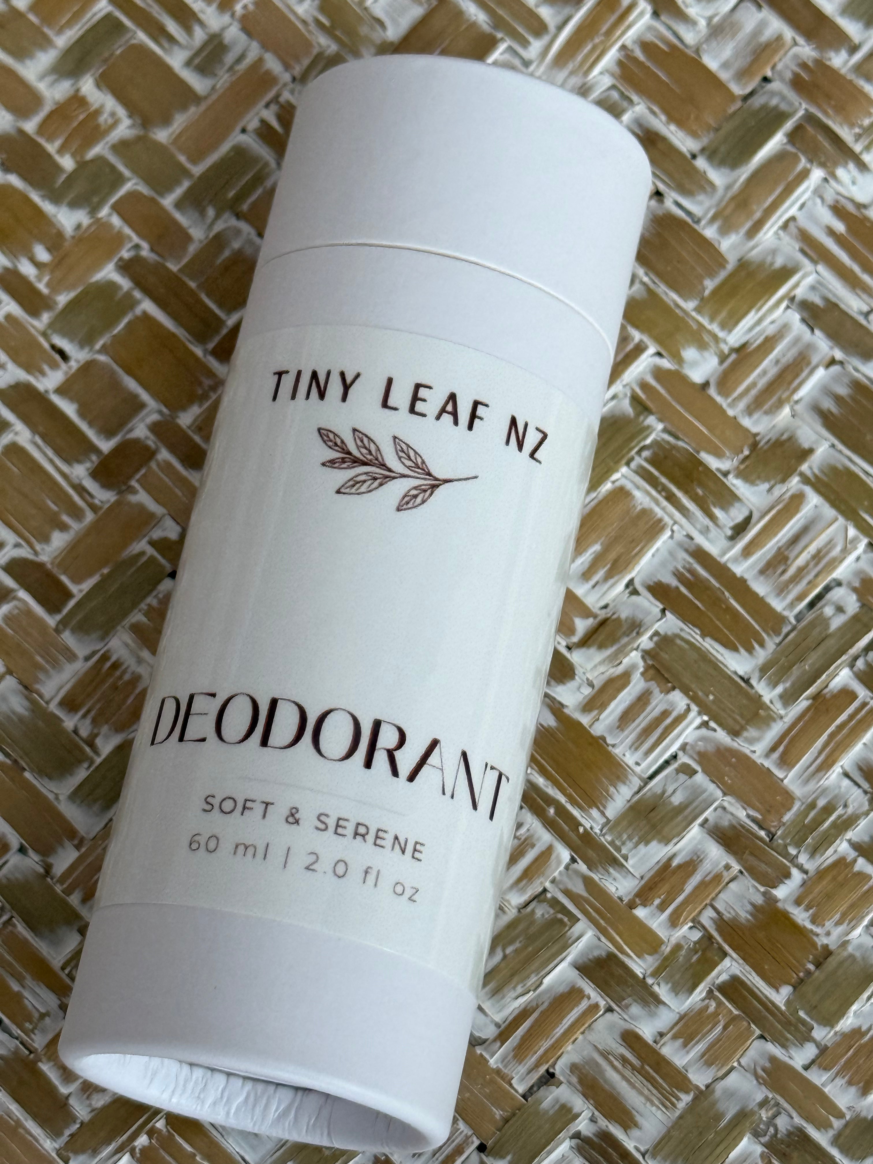 A white cylindrical deodorant stick labeled 'TINY LEAF NZ DEODORANT SOFT & SERENE 60 ml | 2.0 fl oz' placed diagonally on a woven straw mat background.