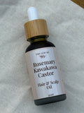 Bottle of Rosemary Kawakawa Castor Hair & Scalp Oil with a dropper on a textured fabric background