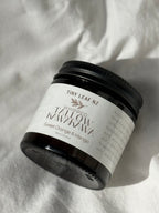A jar of Tiny Leaf NZ Whipped Tallow Manuka Sweet Orange & Mango scented soap, shown on a textured white fabric background with a soft shadow.