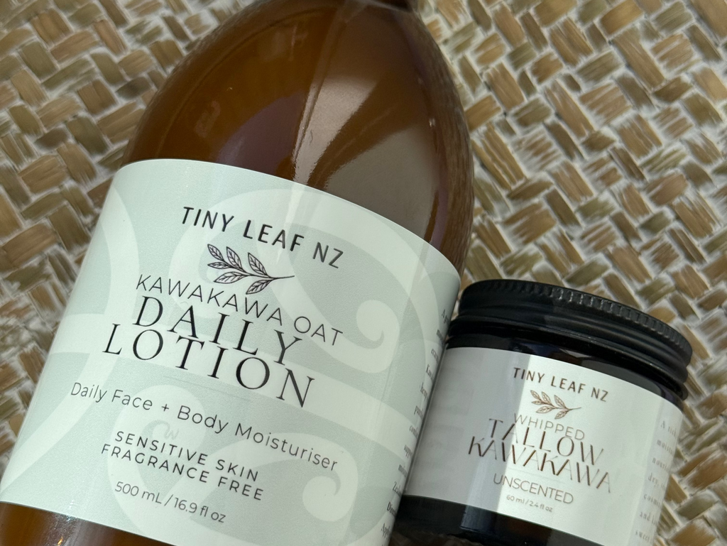 A bottle of Tiny Leaf NZ Kamakawa Daily Lotion with a white dropper cap and a small jar of the same lotion with a black lid, both with white labels, displayed on a woven straw mat.