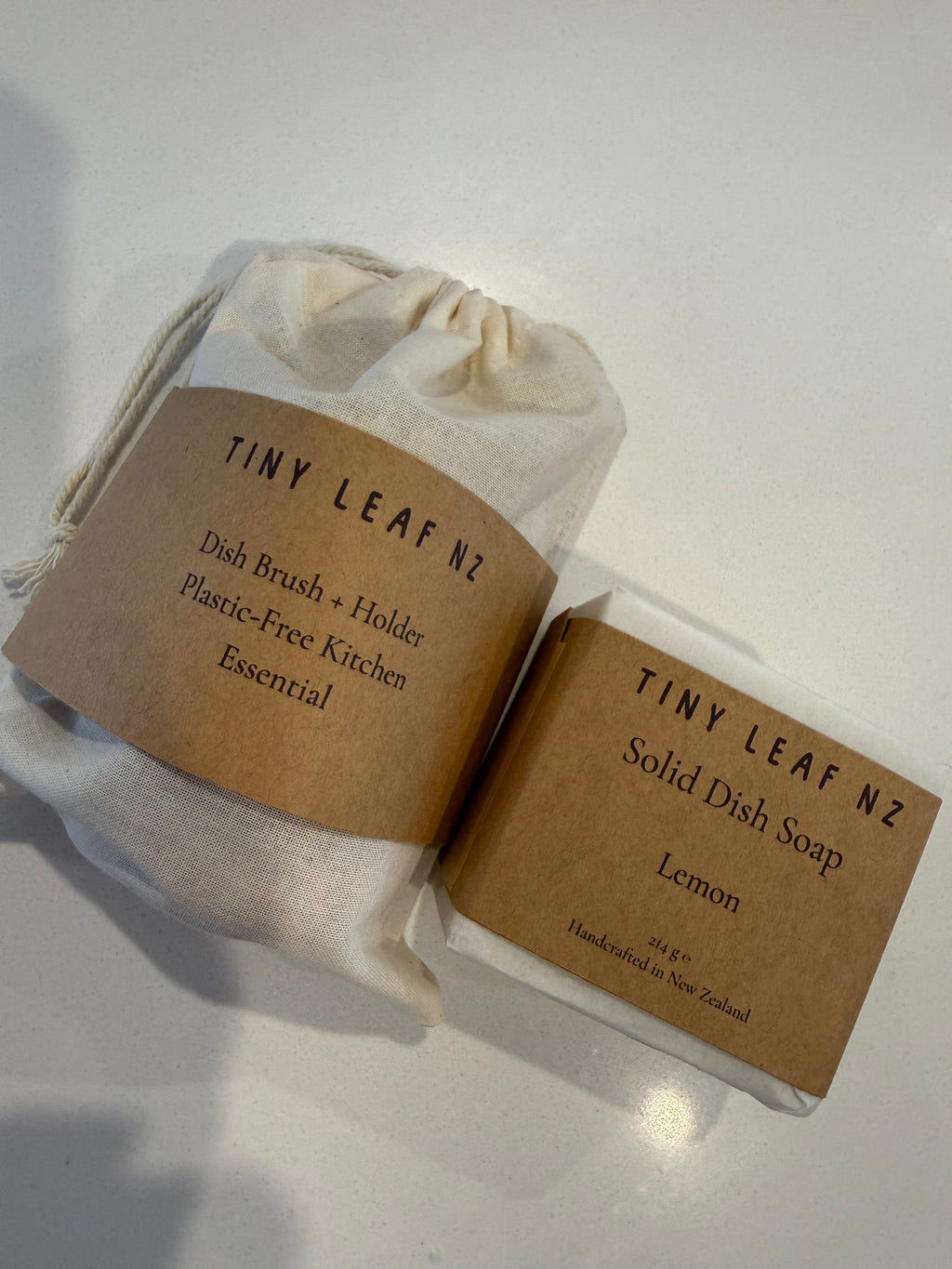 Tiny leaf nz solid dish soap packaged in plastic free packaging and a dish brush packed in a muslin bag with plastic free packaging 