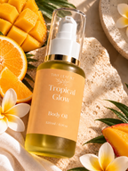 A bottle of Tiny Leaf NZ Tropical Glow Body Oil surrounded by tropical fruits, flowers, and a textured stone surface.