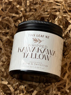 A jar of Tiny Leaf NZ Whipped Kawakawa Tallow unscented pure & sensitive soap, resting on a bed of brown shredded paper packaging filler.