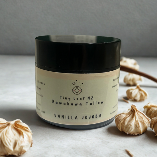Jar of Kawakawa Tallow Vanilla balm with 'Tiny Leaf NZ' label on a soft fabric background
