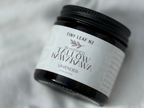 A small black jar of Tiny Leaf NZ 'Whipped Clay Mask' with a white label, resting on a soft, draped white fabric background.