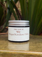 Jar of Tiny Leaf NZ Whipped Kawakawa Tallow on a wooden surface with greenery in the background