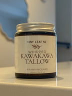 A jar of Tiny Leaf NZ Whipped Kawakawa Tallow Frankincense, 100ml, sitting on a light countertop with a blurred kitchen background.