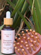 Hair oil bottle and scalp massage brush on a wooden surface with green plants in the background
