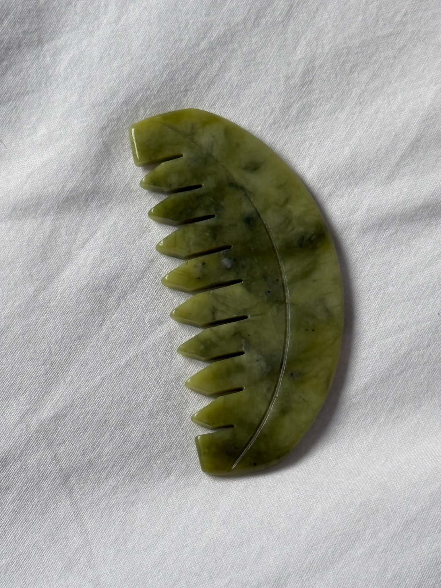 Green jade hair comb on a white fabric background