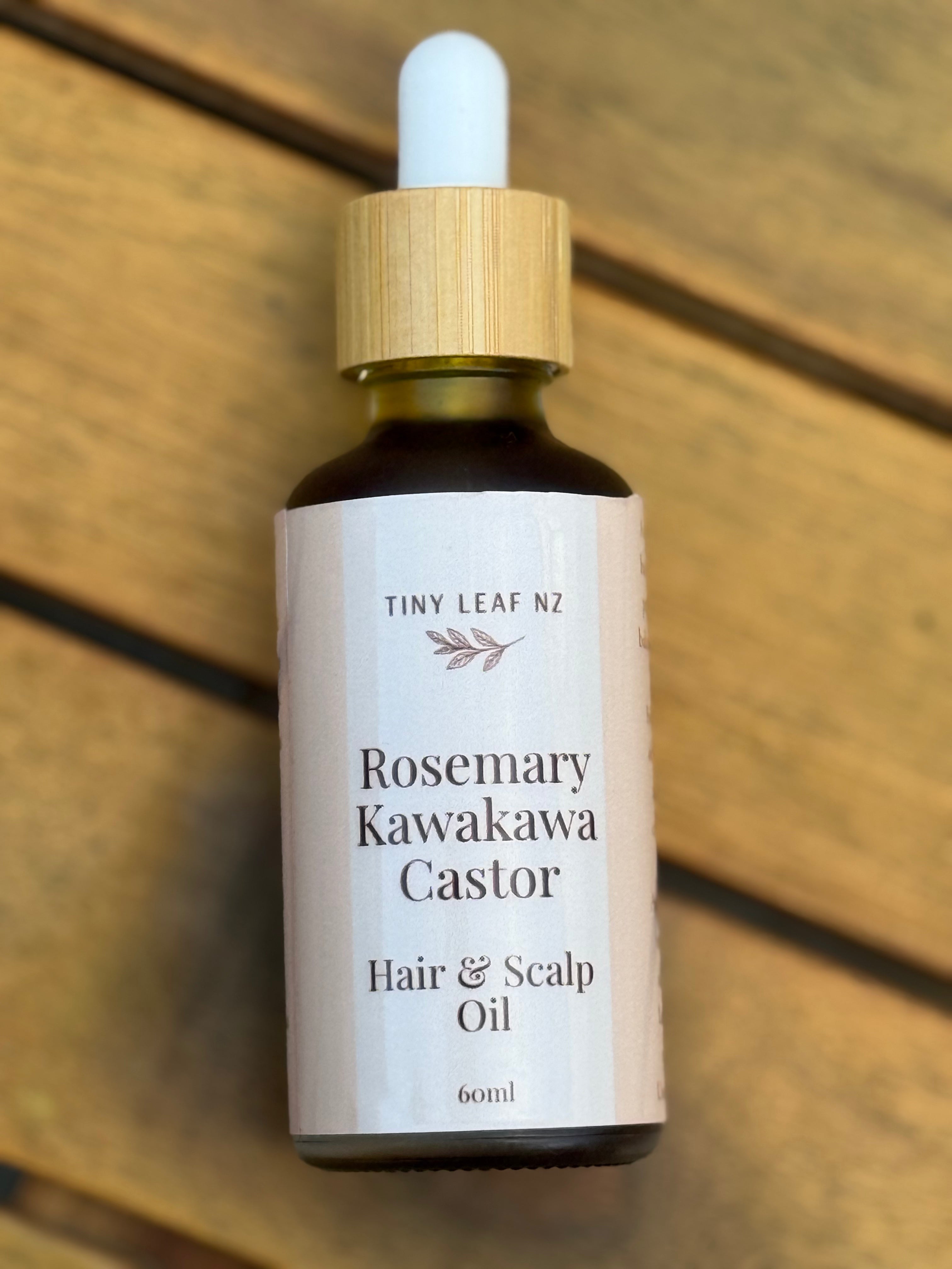 Bottle of Tiny Leaf NZ Rosemary Kawakawa Castor Hair & Scalp Oil on a wooden surface