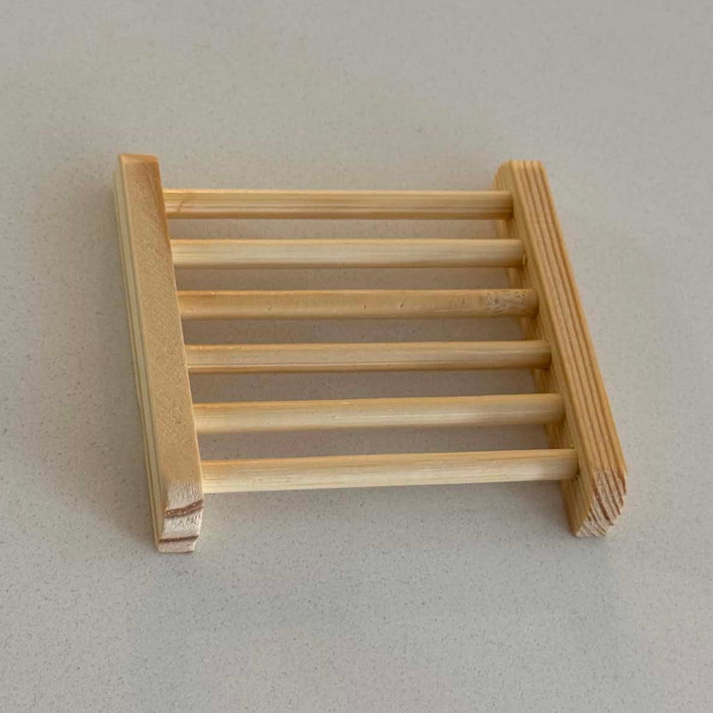 A miniature wooden ladder soap holder made of light natural wood, photographed on a neutral light gray background.