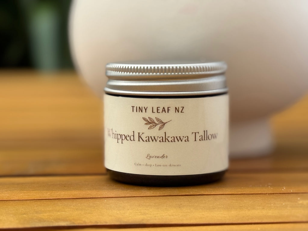 Jar of Tiny Leaf NZ Whipped Kawakawa Tallow on a wooden surface with a blurred background