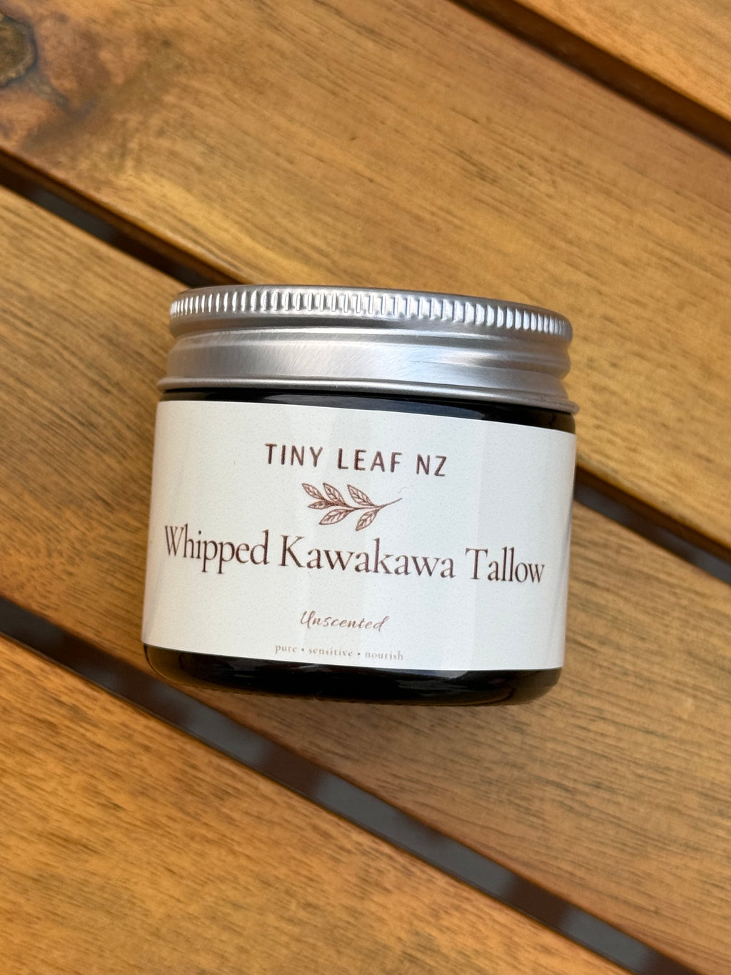 Jar of 'Whipped Kawakawa Tallow' by Tiny Leaf NZ on a wooden surface